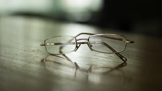 silver-color framed eyeglasses on brown wooden table thumbnail