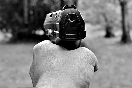 grayscale photography of person holding pistol thumbnail