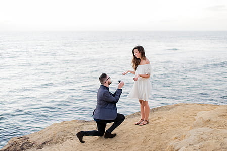 man proposing woman on cliff near ocean during daytime thumbnail