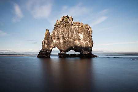 brown rock formation between body of water at daytime thumbnail
