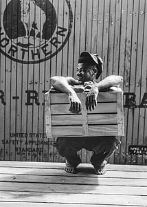 man crouching while holding wooden crate thumbnail