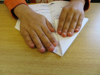 person holding a white printer paper on brown wooden surface thumbnail