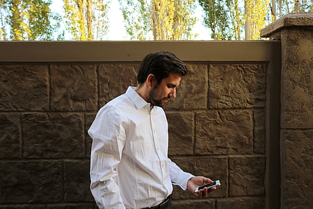 man wearing white dress shirt while holding phone thumbnail