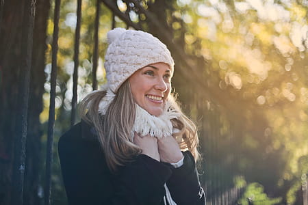 Young Woman in scarf and white skull cap standing in the park during daytime thumbnail