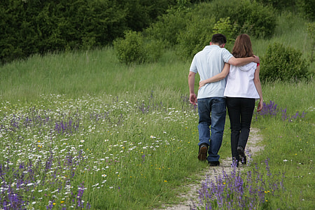 woman in white shirt and man in gray polo shirt hold each holder walk in pathway beside field of flower during daytime thumbnail