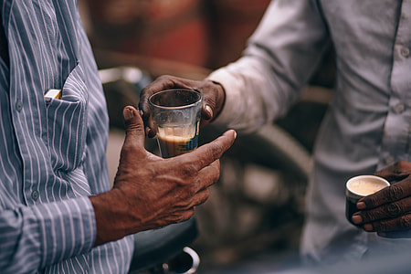 man about to give his drinking glass to man wearing white and blue striped dress shirt thumbnail