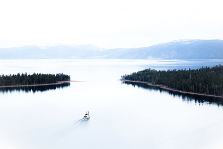 white boat on calm body of water near tress during daytime thumbnail