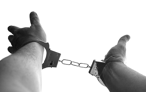 grayscale photography of person's hand with metal handcuffs thumbnail