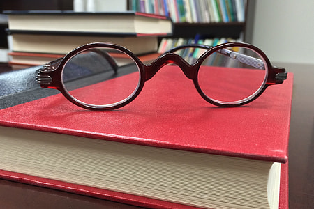 round brown framed eyeglasses on red hardbound book thumbnail