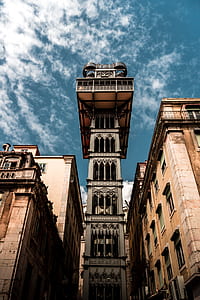 low-angle photo of brown concrete tower under blue sky thumbnail