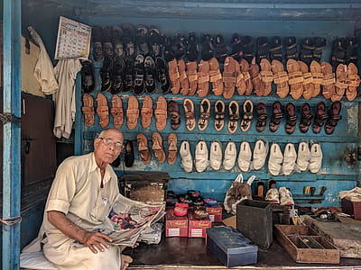Man Reading Newspaper Surrounded by Shoes thumbnail