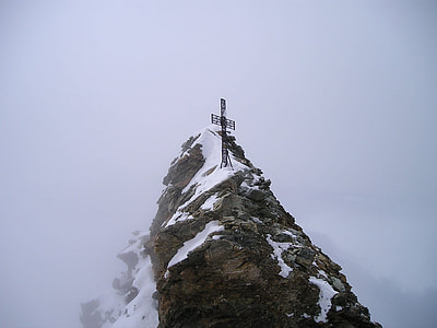 photo of brown metal cross on brown cliff with snow thumbnail
