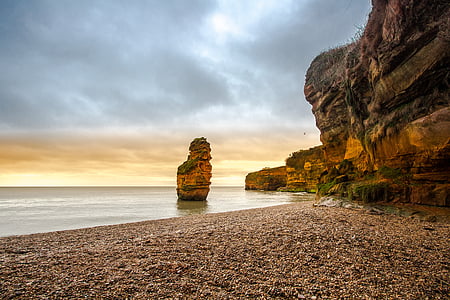 orange rock formation on body of water under gray cloudy sky at daytime thumbnail