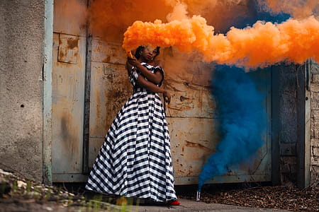 Woman in White and Black Dress Holding Orange Smoke thumbnail