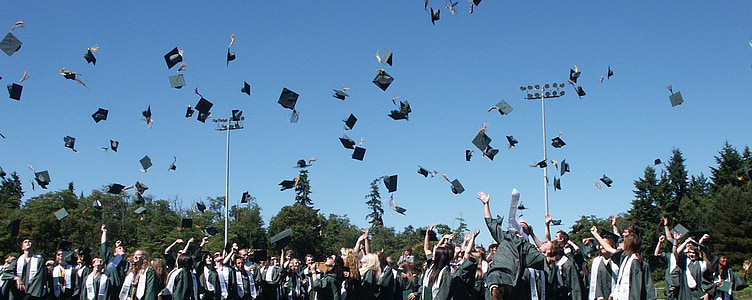students throwing mortar boards in open field at daytime thumbnail