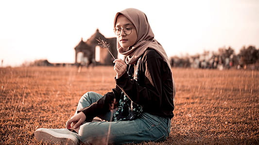 girl sitting on grass field under gray sky thumbnail