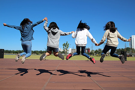 four woman in jacket jumping altogether during daytime thumbnail