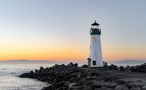 white lighthouse besides body of water at daytime thumbnail