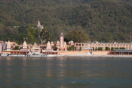 brown concrete buildings near body of water and hill at daytime thumbnail
