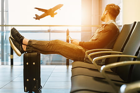 Man looking out window at flying airplane while waiting boarding on aircraft in airport lounge thumbnail