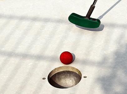 close-up photo of green golf putter and red golf ball near hole thumbnail