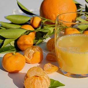 bunch of oranges near filled clear drinking glass thumbnail