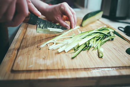 person chopping cucumber on brown board thumbnail