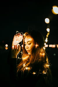 woman holding string lights during night time thumbnail