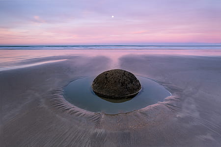 round gray rock in body of water between gray sand at daytime thumbnail