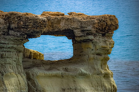brown rock formation near body of water during daytime thumbnail