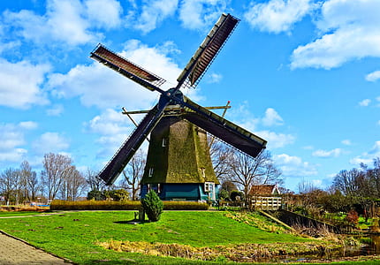 brown and green windmill near green grass under white clouds at daytime thumbnail