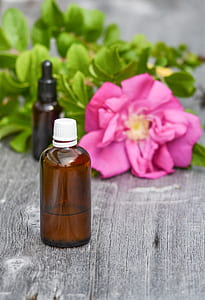 brown glass bottle near pink rose on gray surface thumbnail