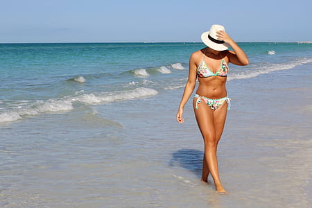 woman wearing white floral bikini walking beside sea at daytime thumbnail
