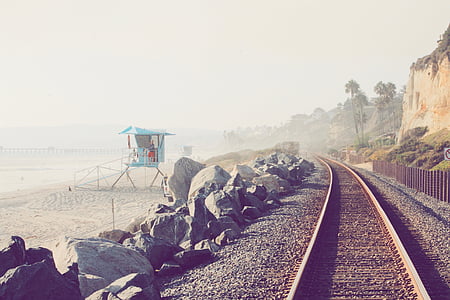 white lifehouse on shore near train track during daytime \ thumbnail