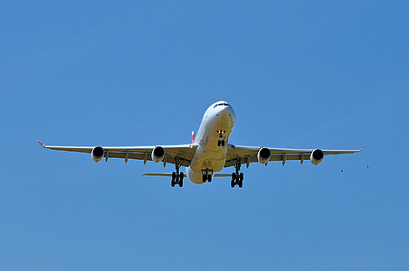 low angle photo of white airplane flying under the blue sky thumbnail