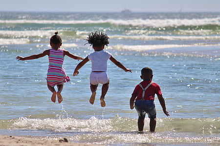three children playing on seashore during daytime thumbnail