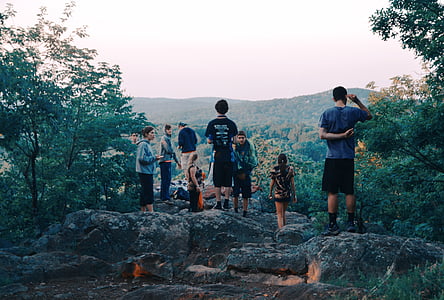 group of children standing on rock beside trees facing overlooking mountan thumbnail