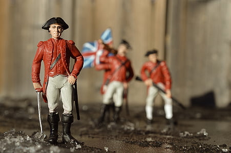 man in maroon and white outfit holding sword figurine in focus photography thumbnail