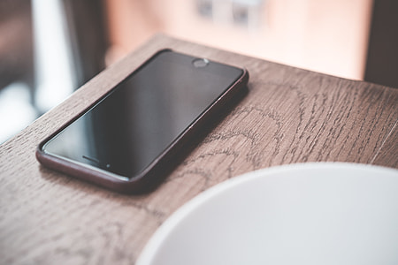 Black Smartphone on Wooden Table in Café thumbnail