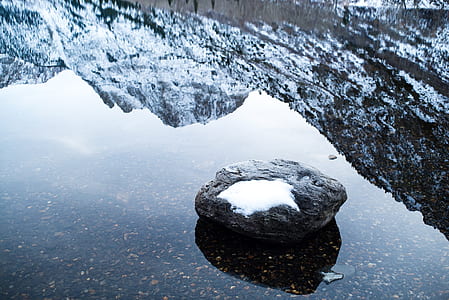 snow covered stone on body of water thumbnail