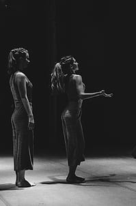 gray scale photo of woman standing in back of woman thumbnail