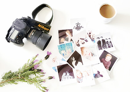flat-lay photography of Nikon DSLR camera and photos beside mug with brown liquid thumbnail