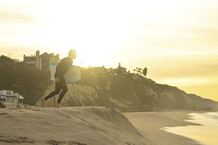 person holding bodyboard running towards the sea thumbnail