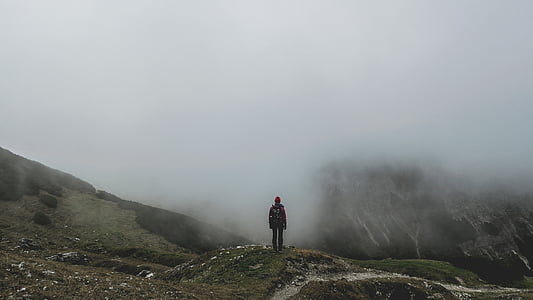 person standing in front of mountains during foggy day thumbnail
