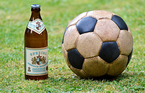 white soccer ball beside brown bottle on grass thumbnail
