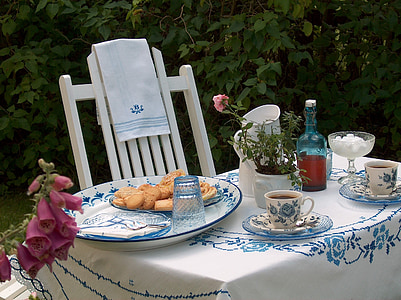 biscuits on top of round white and blue toile ceramic plate on top of white and blue floral table cloth near white wooden Windsor chair on garden during daytime thumbnail