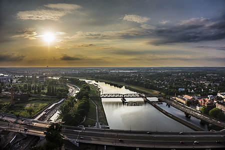 aerial photography of bridge, trees, and buildings under white clouds at daytime thumbnail
