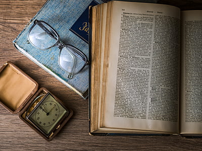 black framed eyeglasses beside book thumbnail