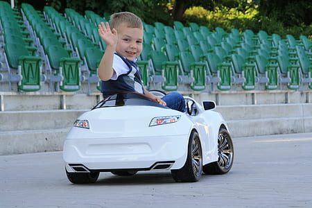 child riding on car toy while waving thumbnail