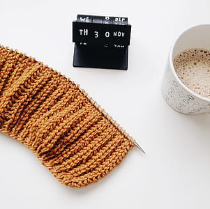 flat-lay photography of brown crochet textile, half-full disposable cup, and black desk calendar thumbnail